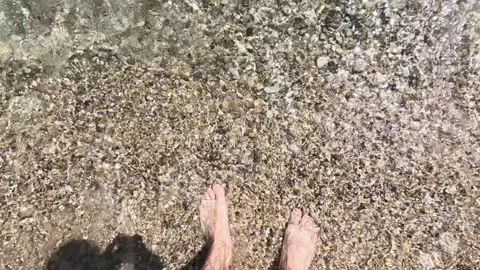 Slow motion as a man walks on the beach and the waves wash his feet, vacati.. Stock Footage 244489182