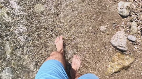 Slow motion as a man walks on the beach and the waves wash his feet, vacati.. 스톡 동영상 244489200