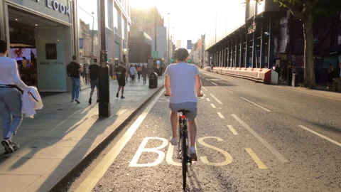 Slow motion man in white t-shirt cycling on busy street in London, England, UK Stock Footage 142005966