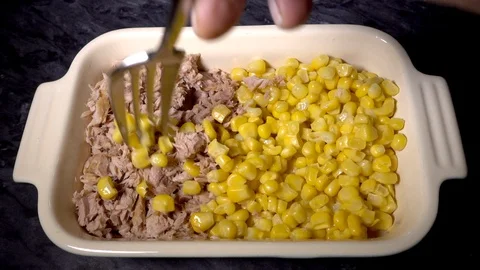Slow motion –  Man's hand mixing sweetcorn with chopped tuna in a dish. Stock Footage 101681733