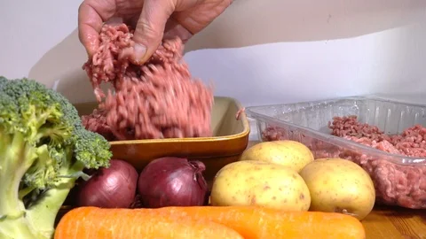 Slow motion - Man’s hand placing raw mince into a baking dish. Stock Footage 102707536