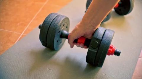 Slow motion of a man's hand placing a dumbbell on the floor after training. Stock Footage 320288559