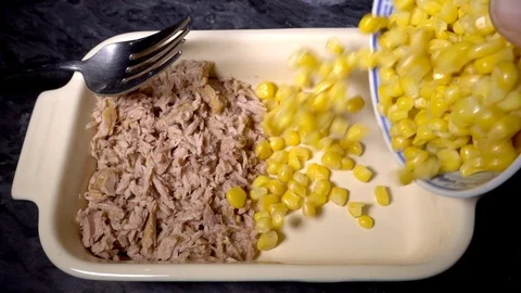 Slow motion –  Man's hand pouring sweetcorn into dish alongside chopped tuna. Stock Footage 101693394