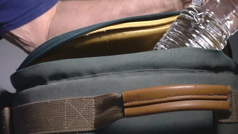 Slow motion – Man’s hand removing a water bottle from a rucksack / backpack. Video stock 98775645