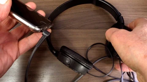 Slow motion - Man’s hands connecting headphones to a mobile phone socket. Video stock 98349322
