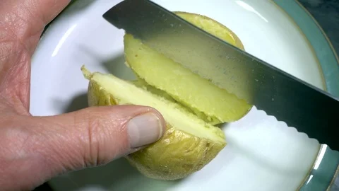 Slow motion - Man’s hands cutting a freshly cooked baked potato in half. Stock-Footage 98291419