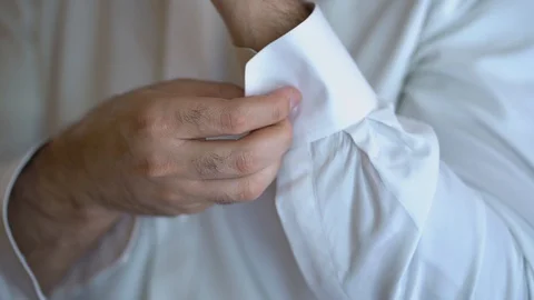 Slow motion. The mans hands fasten a button on the sleeve of a white shirt . Stock Footage 128552288