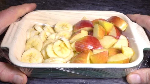 Slow motion - Man’s hands placing cling film over a dish of fruit. Stock-Footage 102486723
