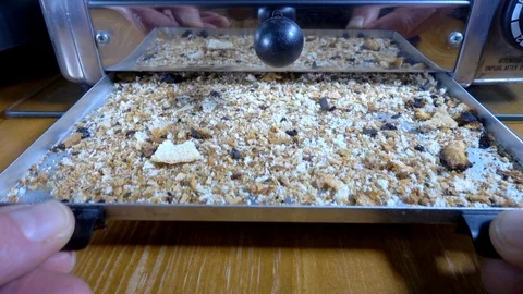 Slow motion – Man's hands pulling out full tray of crumbs from under toaster. Stock Footage 101104115