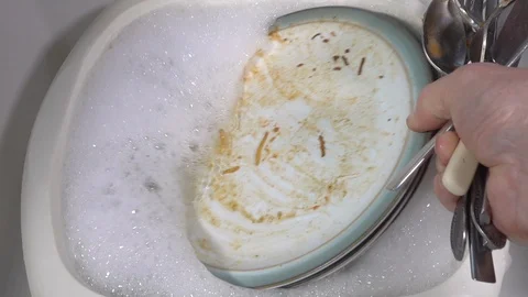 Slow motion - Man’s hands putting dirty washing up into a bowl of soapy water. Stock-Footage 108973362