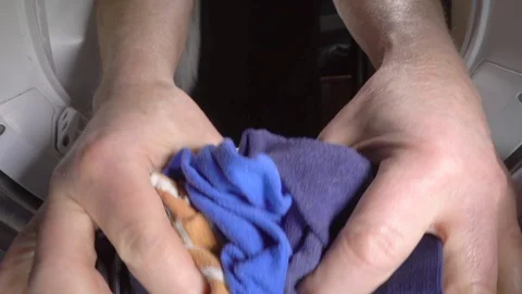 Slow motion – Man’s hands removing clothes from inside a tumble dryer. Stock Footage 103275394