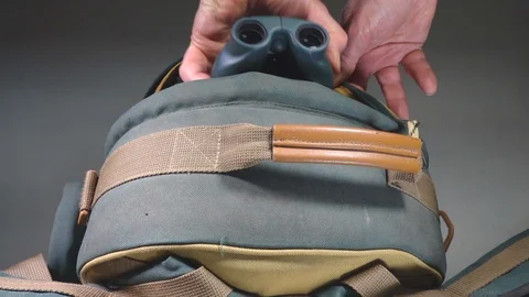 Slow motion – Man’s hands removing binoculars from a rucksack / backpack. Video stock 103314433
