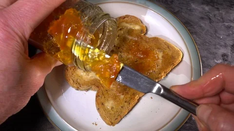 Slow motion - Man’s hands spreading marmalade preserve on buttered toast. Stock Footage 101831763