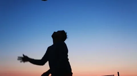 Slow motion of man's silhouette at beach hitting soccer ball with head Stock Footage 65316293