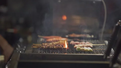 Slow motion of meat grilling over flames at Japanese yatai barbecue at night Stock Footage 321361319