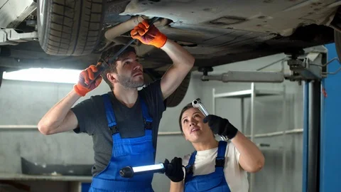 Slow motion, mechanic in gloves repairs a car, woman holds a flashlight Stock Footage 124254728