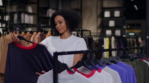 Slow-motion medium shot of a beautiful dark-skinned woman shopping, she admires Видео 267488763