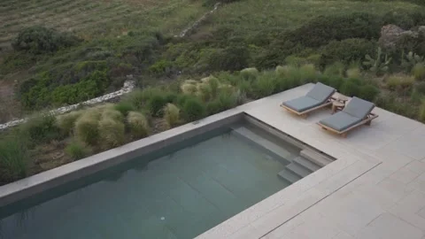 Slow motion medium shot pan of poolside beds and small swimming pool Stock Footage 257948590