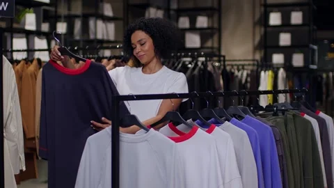 Slow-motion medium shot of a young black woman in a clothing store while Stockbeeldmateriaal 262627965