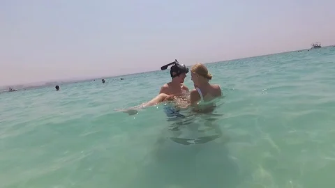 Slow motion of a men holding his girlfriend into his arms in the sea Видео 118067705