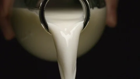 SLOW MOTION: Milk flows from a neck of bottle - Human hand Video stock 72814840