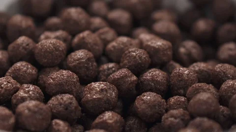 Slow motion milk pour into bowl with chocolate cereal balls Stock Footage