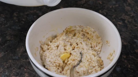 Slow motion milk poured over oats porridge with butter Stock Footage 105706483
