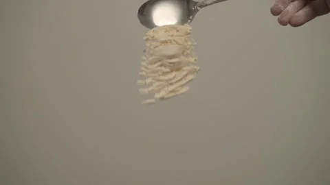 Slow motion of milk powder dropping from spoon Stock Footage 295103713