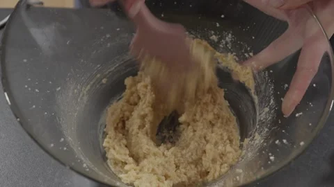 Slow motion Mixing Cookie Dough with Wooden Spoon in Glass Bowl Close Up Stock Footage 328912948