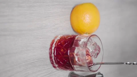 Slow motion of a mixing spoon coming out of an ice-filled glass with red alco Stock Footage 156566257