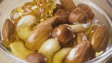Slow motion a mixture of nuts in a bowl is poured honey Stock Footage 85473264