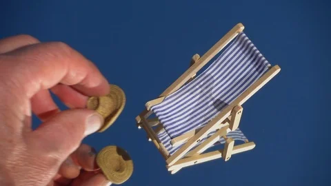 Slow motion: Model deckchair and hat placed onto a blue mirrored surface. Stock Footage 91923064