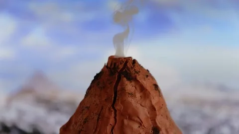 Slow motion of a model of a volcano spewing smoke and a flare of fire at the Stock Footage 162929773