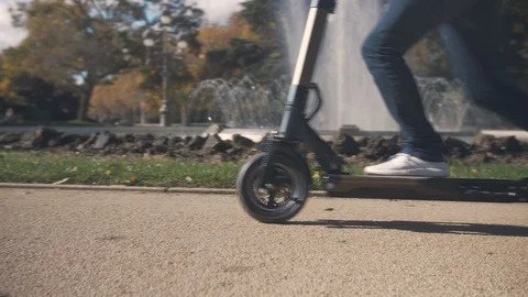 Slow Motion of Modern Man Starting on Electric Scooter in Park with fountain 2 Видео 98757251