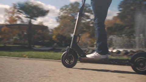 Slow Motion of Modern Man Starting on Electric Scooter in Park with fountain 4 Vidéo 98757360