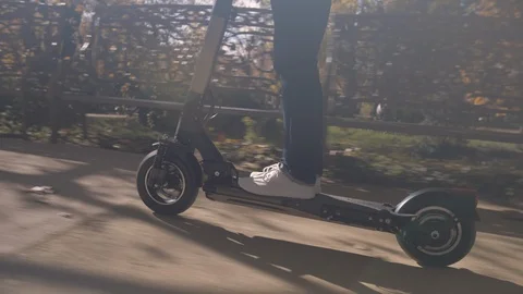 Slow Motion of Modern Man Using Electric Scooter in Sunny Park 2 Vidéo 98757572