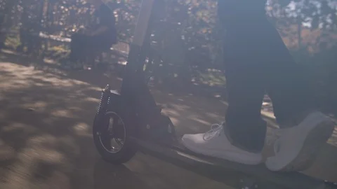 Slow Motion of Modern Man Using Electric Scooter in Sunny Park 1 Vidéo 98757583