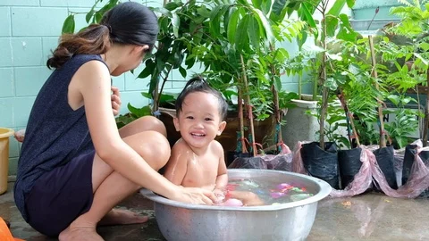 Slow motion. Mom is bathing her children and teasing laugh them happily. Stock Footage 109799921
