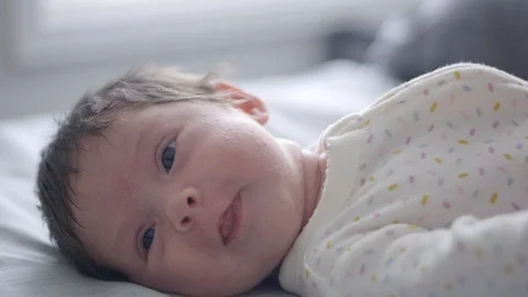 Slow motion of mom giving her baby a kiss while baby looks at camera Stock Footage 107615862