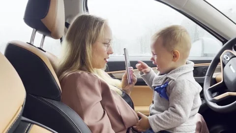 Slow motion. Mom with son and mobile phone fooling around in the car Video stock 209330502