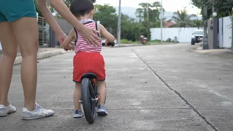Slow motion, mother help support child playing balance bike walking together Stock Footage 94655525