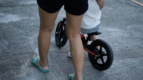 Slow motion, mother help support child playing balance bike walking together Stock Footage 114031435