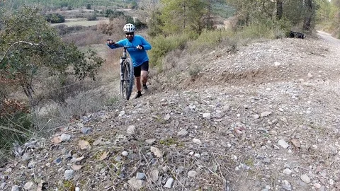 Slow motion of a mountain biker climbing  down a path Stock Footage 124610089