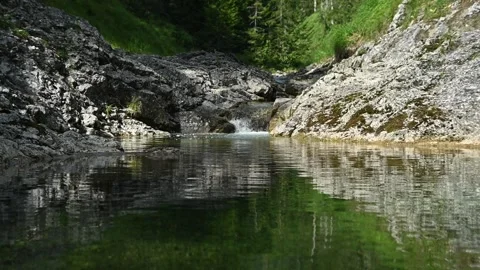 Slow motion of a mountain stream flowing into a pond in summer Stock-Footage 260841900