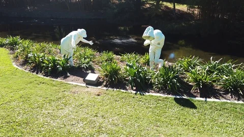 Slow motion move in of two white statues by pond Video stock 108968737