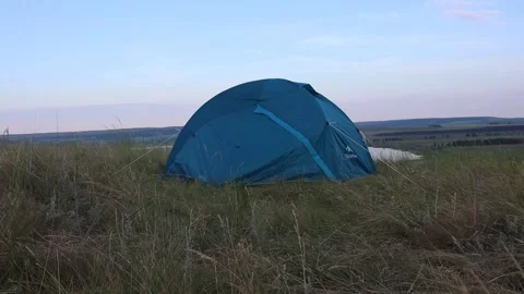 Slow motion from a moving camera to a blue tourist tent standing on the hilly Stock Footage 135953543