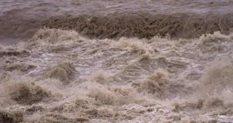 Slow-motion - Muddy stream overflowing its banks Camera tilt down Stock Footage 159305738