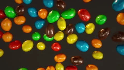 Slow motion multi-colored M&amp;M'S flying on a black background Stock Footage 148680509