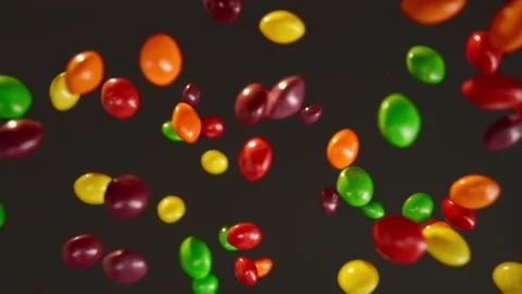 Slow motion multi-colored skittles flying on a black background Stock Footage 148682283
