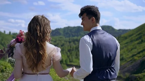 Slow motion. The newlyweds move forward holding hands. Beautiful view of the mou Stock Footage 92720174